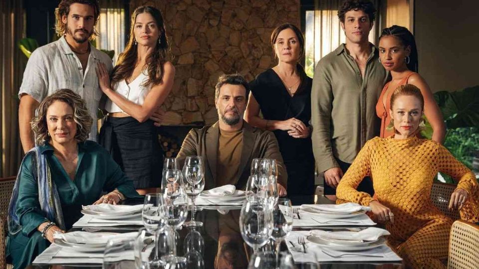 Personagens da novela 'Mania de Você' reunidos ao redor de uma mesa